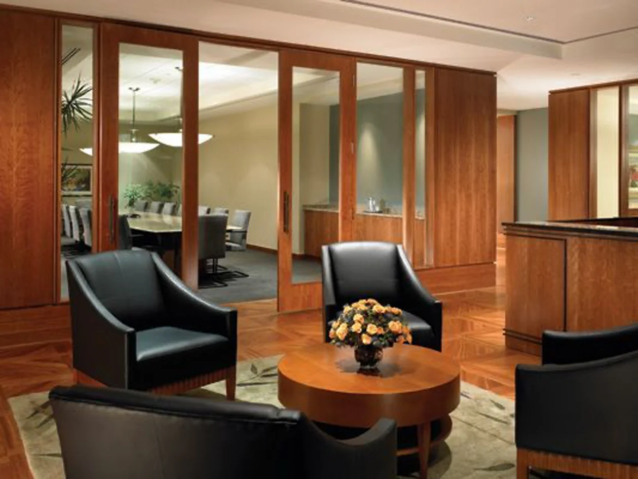 An inviting wood-paneled meeting room with black leather chairs and flowers